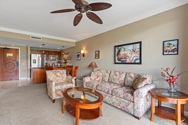 living room featuring ceiling fan, crown molding, and light colored carpet