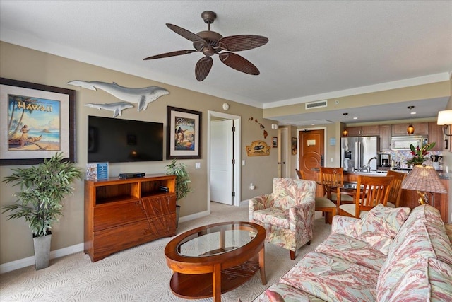 carpeted living room with a textured ceiling, sink, and ceiling fan