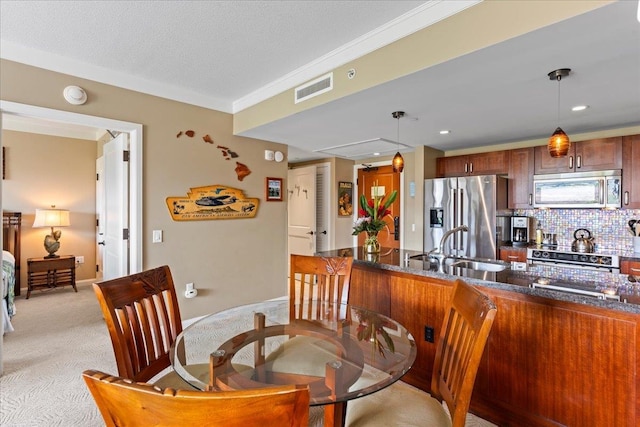 carpeted dining area with ornamental molding, sink, and a textured ceiling