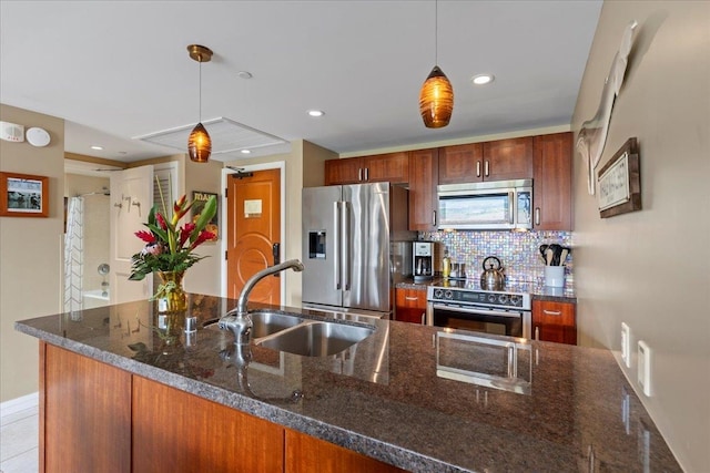 kitchen featuring decorative backsplash, dark stone countertops, stainless steel appliances, sink, and decorative light fixtures