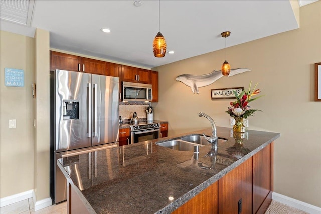 kitchen featuring kitchen peninsula, appliances with stainless steel finishes, dark stone countertops, sink, and decorative light fixtures