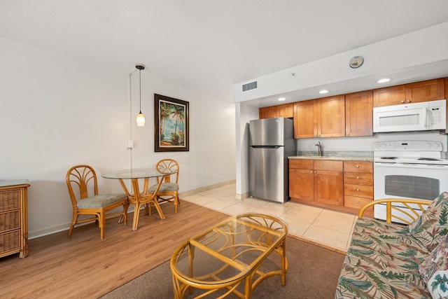 kitchen featuring decorative light fixtures, white appliances, and light tile patterned floors