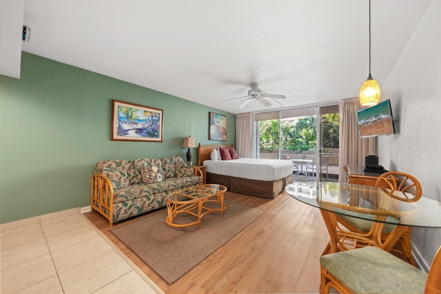 bedroom with ceiling fan, access to exterior, floor to ceiling windows, and light wood-type flooring