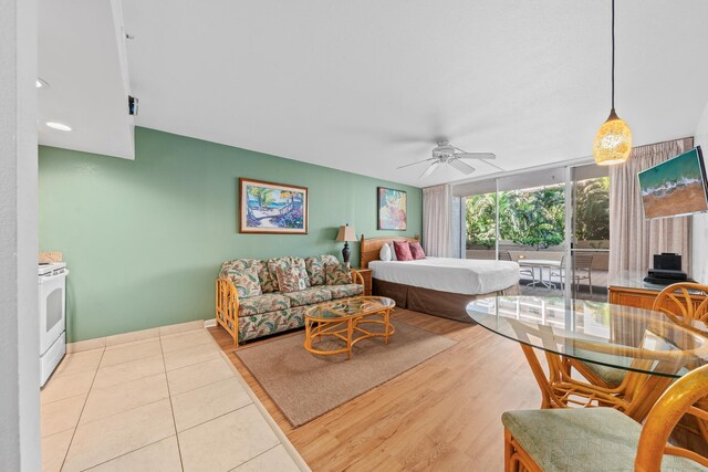 bedroom featuring ceiling fan, a wall of windows, and light hardwood / wood-style flooring