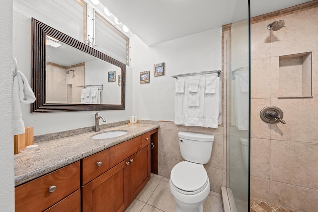 bathroom with toilet, tile walls, tile patterned flooring, tiled shower, and vanity