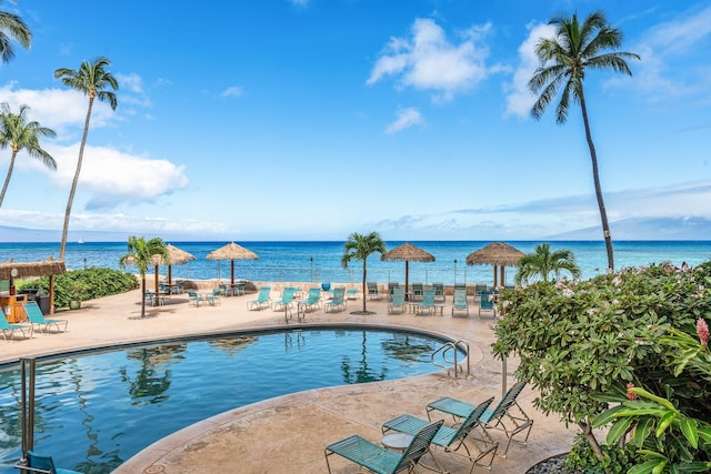 view of swimming pool with a patio area and a water view