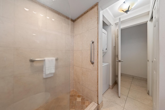 bathroom with stacked washer / dryer, tile patterned flooring, and a tile shower