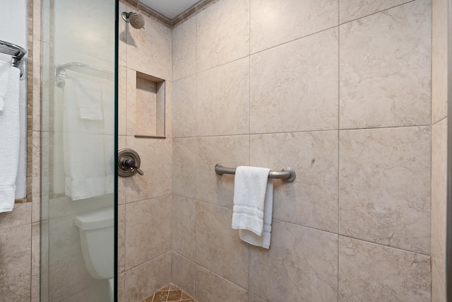 bathroom featuring tiled shower and toilet