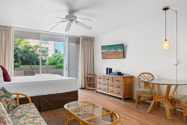 bedroom with light wood-type flooring, ceiling fan, access to exterior, and a wall of windows