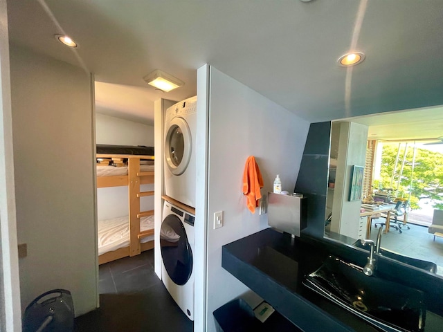 washroom featuring stacked washing maching and dryer and dark tile patterned flooring