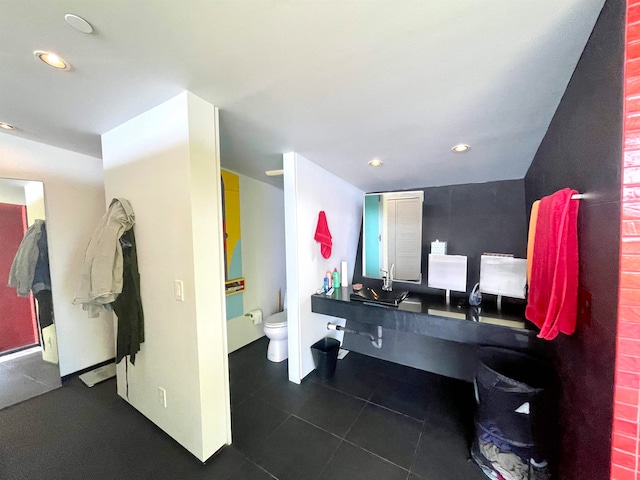 bathroom with toilet, sink, and tile patterned floors