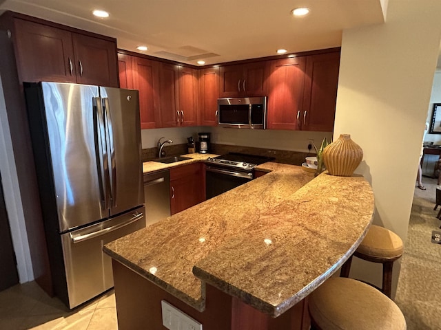 kitchen with stainless steel appliances, a sink, a peninsula, recessed lighting, and light stone counters