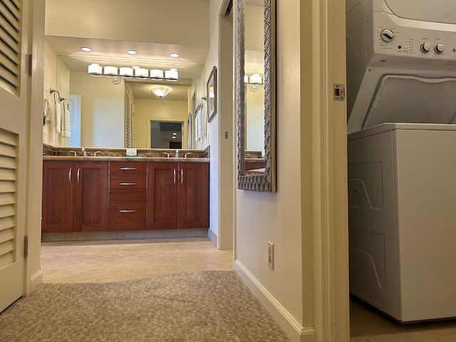 bathroom with estacked washer and dryer, tile patterned floors, baseboards, and double vanity