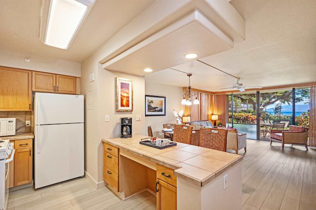 4327 Lower Honoapiilani Rd Unit 101B, Lahaina, HI 96761 - kitchen featuring white appliances, a peninsula, light wood finished floors, a desk, and tile countertops