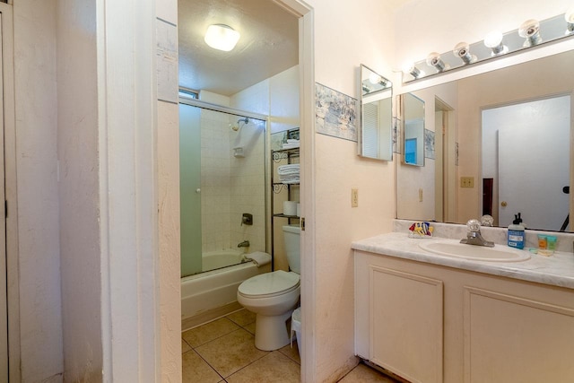 full bathroom with bath / shower combo with glass door, tile patterned flooring, vanity, and toilet