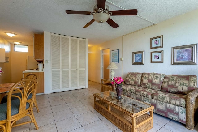 living room featuring ceiling fan, a textured ceiling, and light tile patterned floors