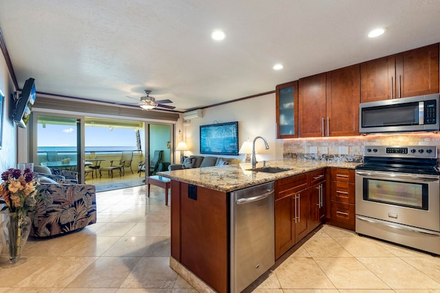 kitchen featuring kitchen peninsula, stainless steel appliances, ceiling fan, crown molding, and sink