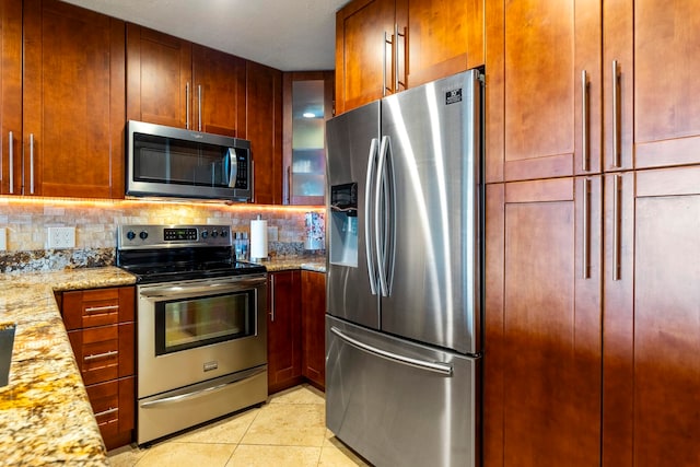 kitchen featuring decorative backsplash, light tile patterned flooring, light stone countertops, and appliances with stainless steel finishes