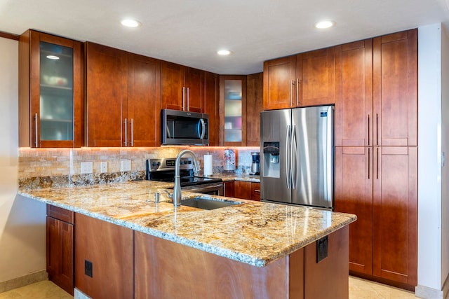 kitchen with kitchen peninsula, appliances with stainless steel finishes, light stone countertops, tasteful backsplash, and sink