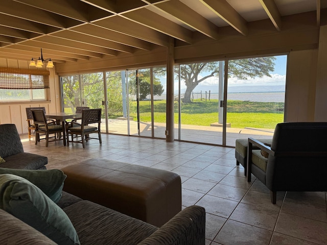 sunroom with a notable chandelier, beamed ceiling, and a water view