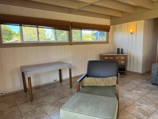 sitting room featuring plenty of natural light, beam ceiling, and light tile floors