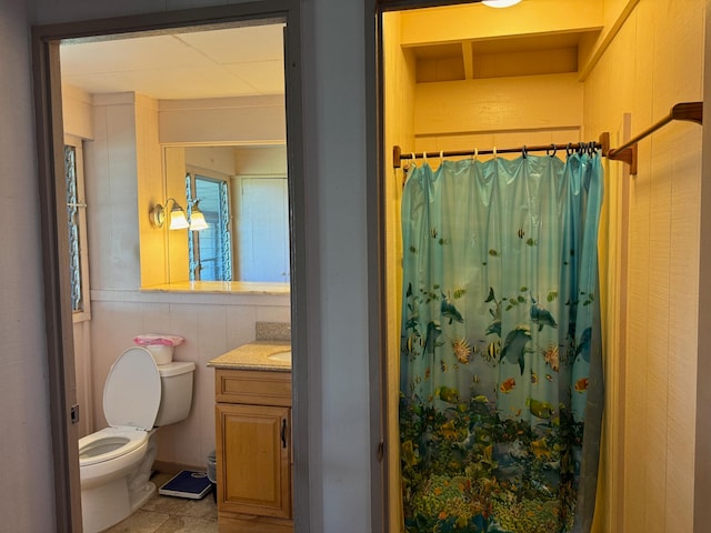 bathroom featuring tile walls, tile floors, toilet, and vanity