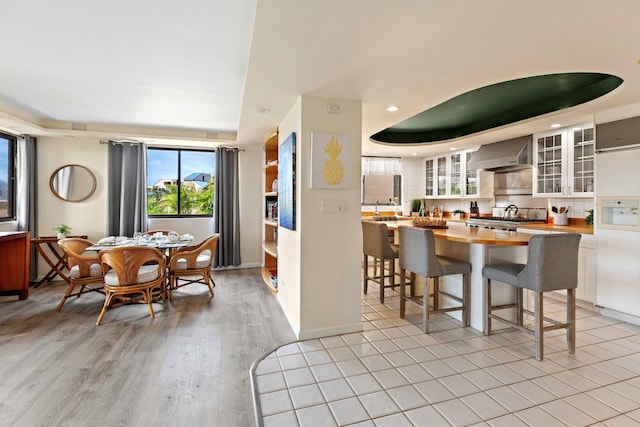 dining space with a raised ceiling and light hardwood / wood-style flooring