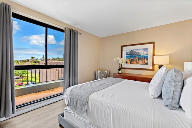 bedroom featuring a baseboard heating unit, access to exterior, and light wood-type flooring