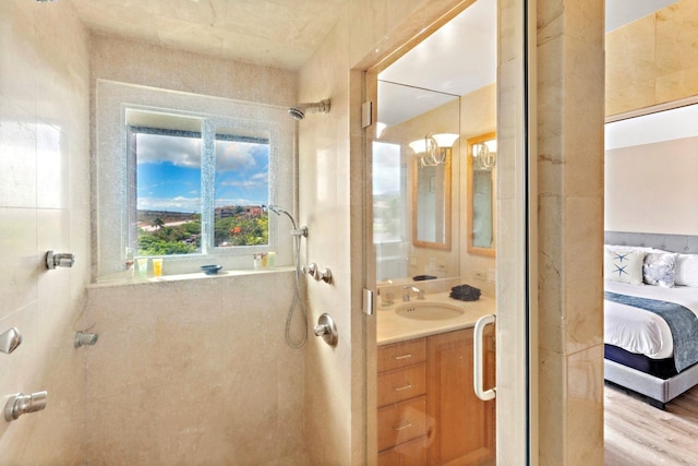 bathroom with hardwood / wood-style flooring, vanity, and tiled shower