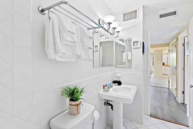 bathroom featuring tile patterned floors, toilet, and tile walls