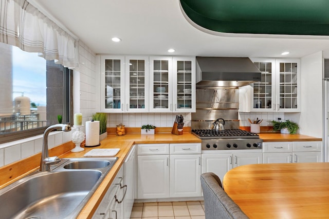 kitchen featuring stainless steel gas stovetop, white cabinetry, sink, wooden counters, and wall chimney exhaust hood