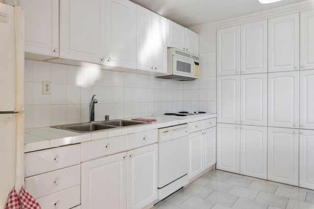 kitchen featuring tile counters, backsplash, white appliances, white cabinets, and sink