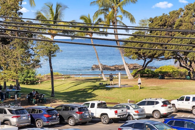 view of car parking with a water view and a lawn