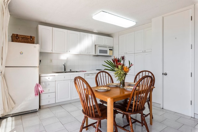 dining area with light tile patterned floors, sink, and a textured ceiling