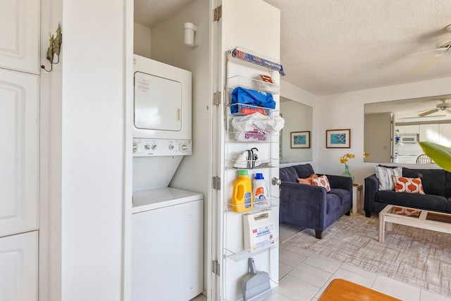 clothes washing area featuring ceiling fan, stacked washer / dryer, a textured ceiling, and light tile patterned flooring