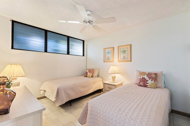 bedroom with ceiling fan, light tile patterned floors, and a textured ceiling