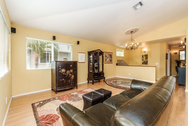 living room featuring vaulted ceiling, an inviting chandelier, and light hardwood / wood-style flooring