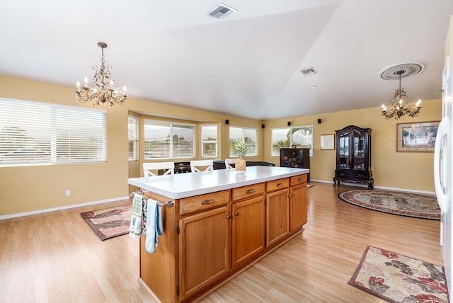 kitchen with light wood-type flooring, a notable chandelier, vaulted ceiling, hanging light fixtures, and a kitchen island