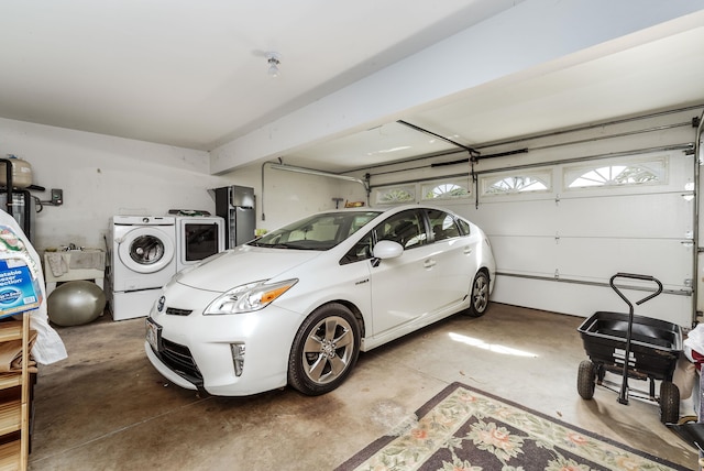 garage with independent washer and dryer and stainless steel refrigerator