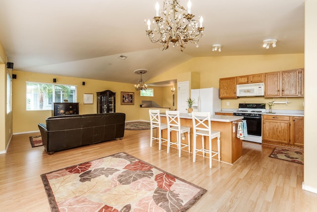 kitchen featuring hanging light fixtures, white appliances, a kitchen bar, a chandelier, and vaulted ceiling