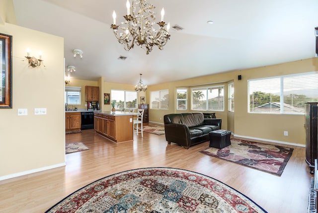 living room featuring an inviting chandelier, light wood-type flooring, and vaulted ceiling