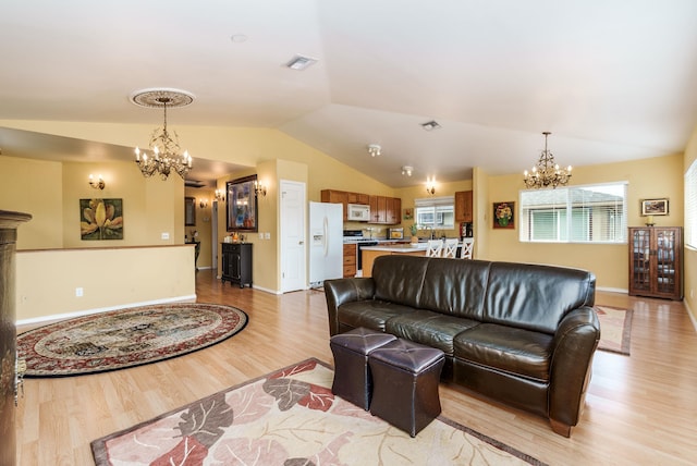 living room featuring an inviting chandelier, light wood-type flooring, sink, and vaulted ceiling