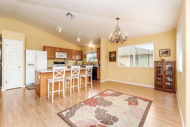 kitchen with a breakfast bar, white appliances, a kitchen island, light hardwood / wood-style flooring, and decorative light fixtures