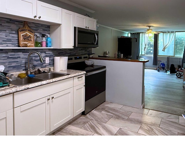 kitchen featuring white cabinets, a sink, backsplash, and appliances with stainless steel finishes