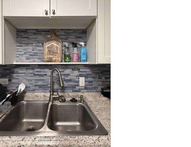 kitchen featuring decorative backsplash, white cabinets, and a sink