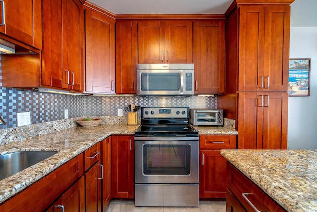 kitchen featuring appliances with stainless steel finishes, sink, light stone counters, and decorative backsplash