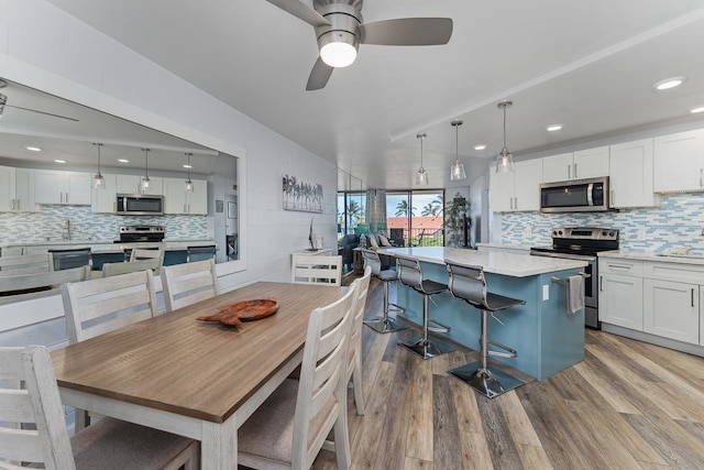 dining space featuring sink, ceiling fan, and light wood-type flooring