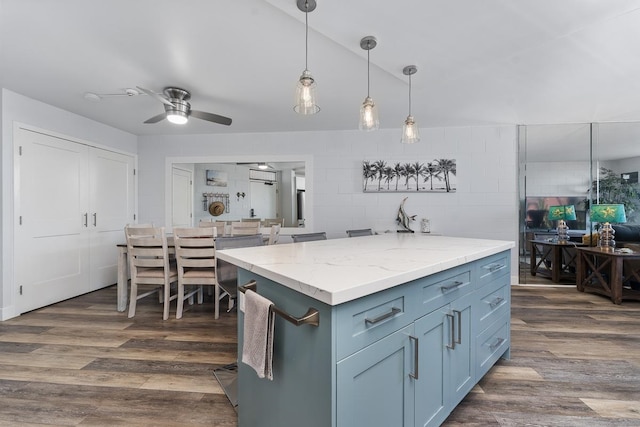 kitchen with light stone countertops, dark wood-type flooring, tile walls, ceiling fan, and hanging light fixtures