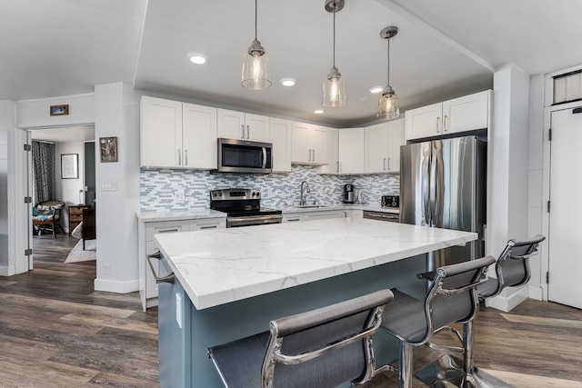 kitchen with dark hardwood / wood-style flooring, appliances with stainless steel finishes, decorative backsplash, white cabinetry, and hanging light fixtures