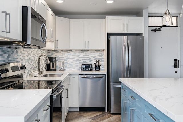 kitchen featuring light hardwood / wood-style flooring, backsplash, white cabinetry, appliances with stainless steel finishes, and sink